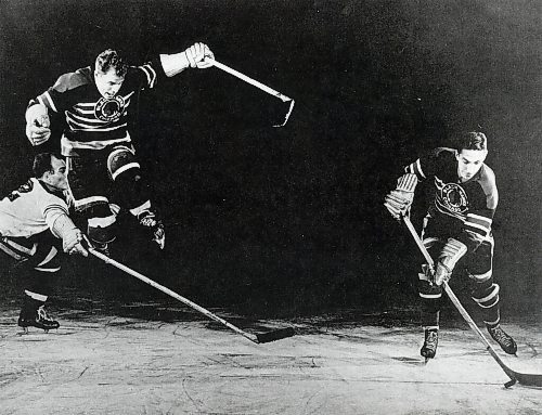 Canstar Community News High-flying Billy Mosienko soars over a defender's stick as his linemate pushes the puck up the ice.