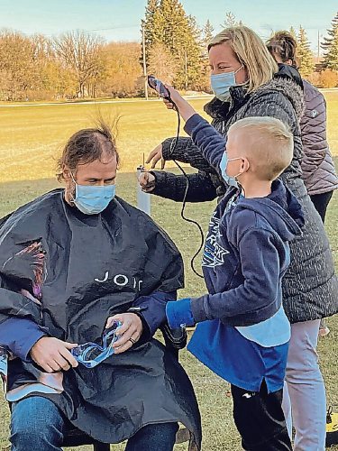 Canstar Community News Nov. 8, 2021 - Starbuck School principal Dale Fust receives a haircut from the top student fundraiser, Ryker Milne (right) and his mother Alison, another teacher at the school. (SUPPLIED PHOTO)