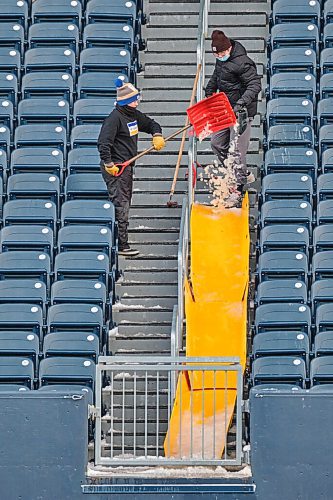 MIKE DEAL / WINNIPEG FREE PRESS
Kids shovel snow and ice in preparation of the upcoming game while the Winnipeg Blub Bombers practice at IG Field Friday morning.
211126 - Friday, November 26, 2021.