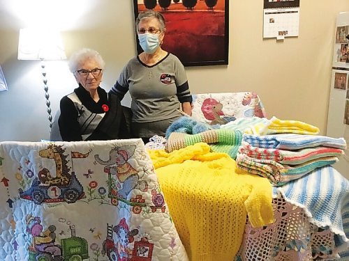 Canstar Community News Jean Brydges and Ramy Remedios show off some of the lap blankets theyve created, the Christ the King beige and green blanket sits at the centre.
