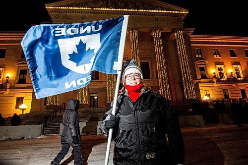 Mike Sudoma / Winnipeg Free Press
Mona Simcoe of the Union of National Defence Employees waves a UNDE as she stands in support of the Rally for Remebrance held at the Manitoba Legislative building Monday evening. 
December 6, 2021