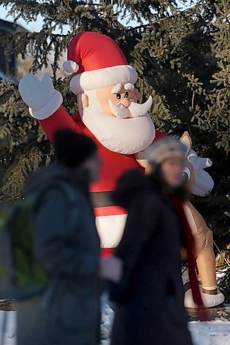 SHANNON VANRAES / WINNIPEG FREE PRESS
Pedestrians stroll past a giant inflatable Santa on Wellington Crescent on December 9, 2021.