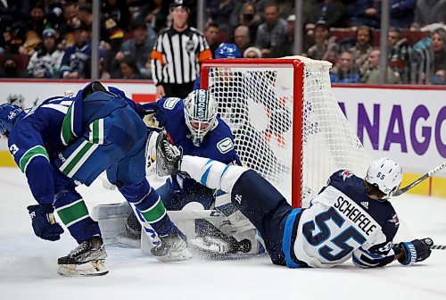 Winnipeg Jets' Mark Scheifele (55) is tripped by Quinn Hughes (43) as he tries to shoot on Vancouver Canucks' goaltender Thatcher Demko (35) during second period NHL hockey action in Vancouver, BC, Friday, December 10, 2021. (TREVOR HAGAN / WINNIPEG FREE PRESS)