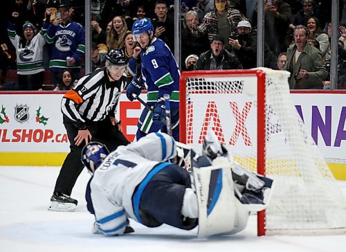 Winnipeg Jets' goaltender Eric Comrie (1) dives behind himself to stop a puck on the goal line during a shootout attempt by Vancouver Canucks' J.T. Miller (9) during the shootout, Friday, December 10, 2021. (TREVOR HAGAN / WINNIPEG FREE PRESS)