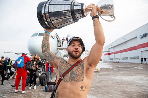 MIKE DEAL / WINNIPEG FREE PRESS
Winnipeg Blue Bombers and Grey Cup Champion Brady Oliveira carries the trophy across the tarmac as the team arrives home from Hamilton Monday afternoon.
211213 - Monday, December 13, 2021.