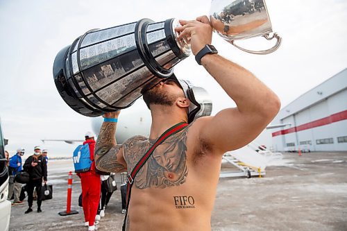 MIKE DEAL / WINNIPEG FREE PRESS
Winnipeg Blue Bombers and Grey Cup Champion Brady Oliveira carries the trophy across the tarmac as the team arrives home from Hamilton Monday afternoon.
211213 - Monday, December 13, 2021.