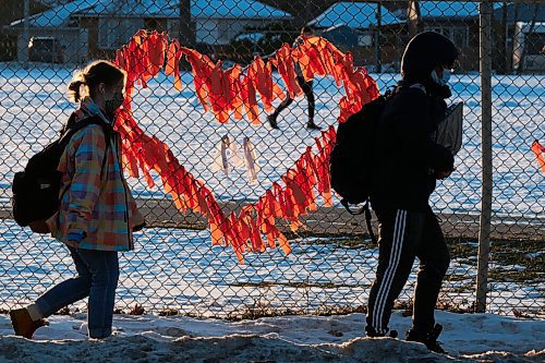 MIKE DEAL / WINNIPEG FREE PRESS
Late afternoon sunlight illuminates orange ribbons on the schoolyard fence at Kelvin High School just as classes are dismissed for the day. The ribbons are a memorial to the unmarked graves at a former residential schools that were discovered this year across the country. 
211214 - Tuesday, December 14, 2021.