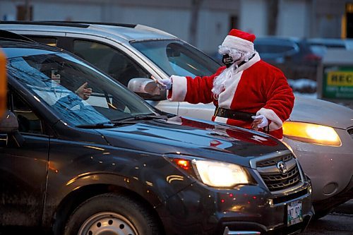 MIKE DEAL / WINNIPEG FREE PRESS
Santa is helping the Downtown Winnipeg BIZ launch its brand-new Downtown Winnipeg Gift Card program by handing out gift cards to passersby at Donald and Broadway early Friday morning. The first program of its kind for Winnipeg is aimed to help downtown businesses recover. 
211217 - Friday, December 17, 2021.