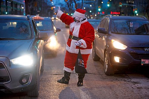 MIKE DEAL / WINNIPEG FREE PRESS
Santa is helping the Downtown Winnipeg BIZ launch its brand-new Downtown Winnipeg Gift Card program by handing out gift cards to passersby at Donald and Broadway early Friday morning. The first program of its kind for Winnipeg is aimed to help downtown businesses recover. 
211217 - Friday, December 17, 2021.