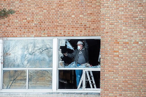 Mike Sudoma / Winnipeg Free Press
A worker pulls glass out of a broken window on the first floor of St James Collegiate Sunday afternoon after a fire broke out Sunday morning. 
December 19, 2021