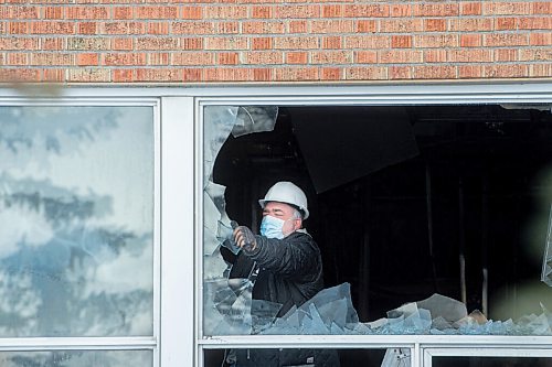 Mike Sudoma / Winnipeg Free Press
A worker pulls glass out of a broken window on the first floor of St James Collegiate Sunday afternoon after a fire broke out Sunday morning. 
December 19, 2021