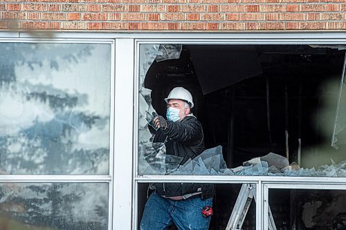 Mike Sudoma / Winnipeg Free Press
A worker pulls glass out of a broken window on the first floor of St James Collegiate Sunday afternoon after a fire broke out Sunday morning. 
December 19, 2021