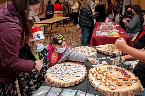 Mike Sudoma / Winnipeg Free Press
(Right to left) Illianah and her brother William take turns choosing buttons from the Mikinaak Buttons table at the Indigenous Arts Market at Canad Inns Polo Park with their mother, Alexandria Sunday morning
December 19, 2021
