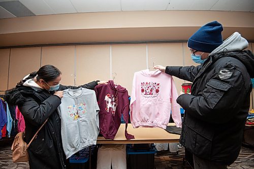 Mike Sudoma / Winnipeg Free Press
Destinee Comegan and Issac Dyck look over sweaters at Red Road Clothings booth at the Indigenous Arts Market held at Canad inns Polo Park Sunday morning
December 19, 2021