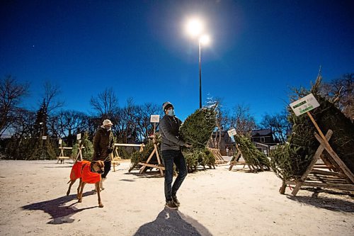 Mike Sudoma / Winnipeg Free Press
Alex (right), Maria (left) and their pup Reginald haul a tree back to their car at the 67th Winnipeg Scout Group Christmas Tree Lots held at the Corydon Community Centre Monday evening
December 20, 2021