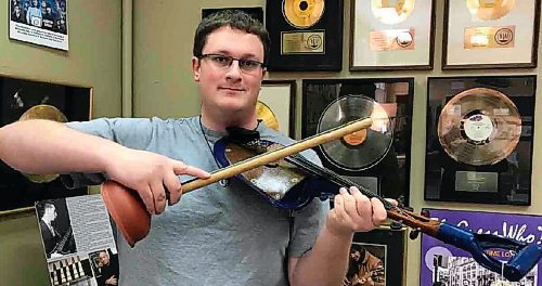 Canstar Community News Jared Warkentin poses at the St. Vital Museum with a shovel fiddle (and a plunger bow) once owned by Jimmy Moore.