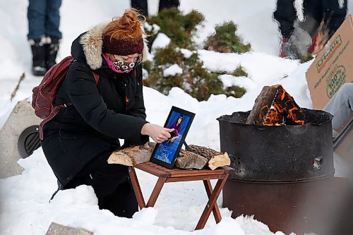 JOHN WOODS / WINNIPEG FREE PRESS
A woman touches a photo just before putting tobacco in a fire at a memorial/celebration of life for musician Vince Fontaine at Oodena Circle at the Forks Sunday, January 16, 2022. 

Re: ?
