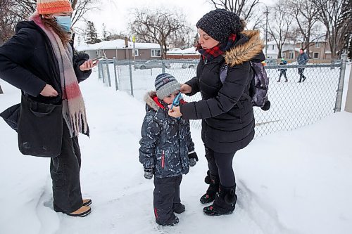 MIKE DEAL / WINNIPEG FREE PRESS
Tiffany Munro puts on a mask for her son Maverick, 5, as he heads to school Monday morning.
Parents drop off kids at Carpathia School, 300 Carpathia Road, Monday morning. 
See Maggie Macintosh story
220117 - Monday, January 17, 2022.