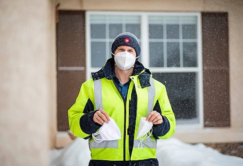 JESSICA LEE / WINNIPEG FREE PRESS

Letter-carrier Corey Gallagher poses for a photo at his home on January 18, 2022. He was sent home earlier in the day from his work at Canada Post because his boss said he couldnt wear a medical grade N95 to work. The supervisors and superintendent insisted he wear the provided cloth mask he is holding in his left hand. He holds the N95 he was initially wearing to work in his other hand. 

Reporter: Dylan






