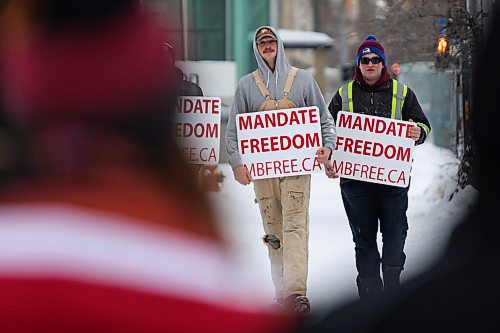 Daniel Crump / Winnipeg Free Press. People carry signs as the trucker convoy protest at the Manitoba legislature continues Saturday in Winnipeg. February 5, 2022.