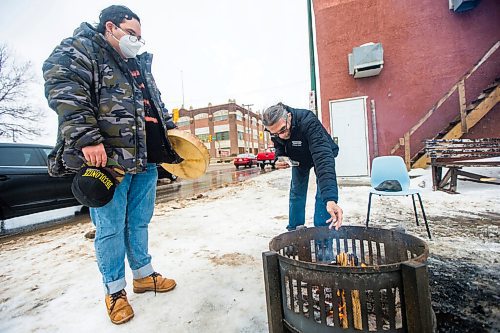 MIKAELA MACKENZIE / WINNIPEG FREE PRESS

George Spence puts tobacco in the warming fire as Davey Cole watches at Sunshine House in Winnipeg on Tuesday, Feb. 8, 2022. For Eva Wasney story.
Winnipeg Free Press 2022.