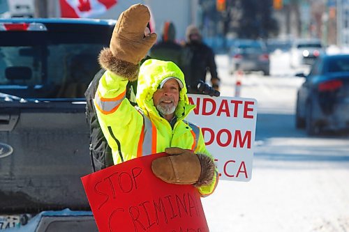 MIKE DEAL / WINNIPEG FREE PRESS
Doug Stern waves at cars passing on Broadway along with other protestors Friday morning at the convoy protest in front of the Manitoba Legislative building. 
220211 - Friday, February 11, 2022.