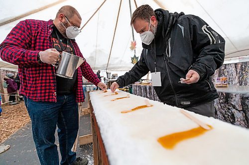 Daniel Crump / Winnipeg Free Press. Dan Girouard (left) and Marc Gilbert (right) make maple taffy, also known as tire d?rable in French, on the first day of Festival du Voyageur in Winnipeg. The Festival returns for the first time since prior to the pandemic. February 19, 2022.