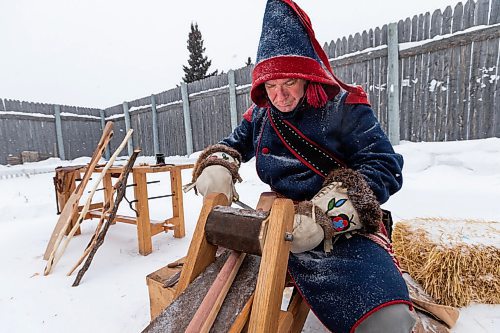 Daniel Crump / Winnipeg Free Press. Mark Blieske works on making a wooden paddle using traditional tools at Festival du Voyageur in Winnipeg. Many of the people who reenact traditional life at the fort that would normally work inside the forts structures must ply their craft outside this year due to pandemic precautions. February 19, 2022.