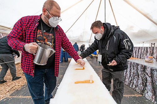Daniel Crump / Winnipeg Free Press. Dan Girouard (left) and Marc Gilbert (right) make maple taffy, also known as tire d?rable in French, on the first day of Festival du Voyageur in Winnipeg. The Festival returns for the first time since prior to the pandemic. February 19, 2022.