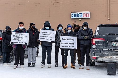 Daniel Crump / Winnipeg Free Press. Friends of John Lloyd Barrion hold signs during a vigil in his honour. The 19-year-old was killed while working at the beer vendor attached to the Travelodge on Notre Dame Ave. February 19, 2022.