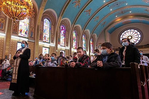 Daniel Crump / Winnipeg Free Press. Reverend Ihor Shved (left) leads a group of kids in prayer at the Ukrainian Catholic Metropolitan Cathedral of Sts. Volodymyr and Olha. March 5, 2022.