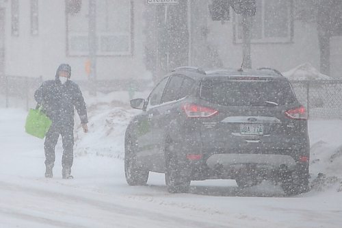Daniel Crump / Winnipeg Free Press. A person walks to their car parked on Arlington street as heavy and blowing snow make for treacherous road conditions Saturday afternoon. March 12, 2022.