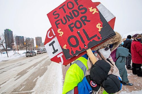Daniel Crump / Winnipeg Free Press. Joanne Marks, a volunteer with Manitoba Energy Justice Coalition, holds signs during a climate rally. Around 50 people attended the rally in front of the Canadian Museum for Human Rights at noon on Saturday. March 12, 2022.