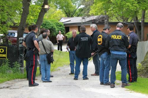 Winnipeg Police officers and provincial justice personnel enter a Hells Angels clubhouse in Winnpeg on August 5, 2010, after a raid. THE CANADIAN PRESS/ Winnipeg Free Press
