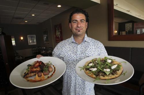 MIKE.DEAL@FREEPRESS.MB.CA 100811 - Wednesday, August 11, 2010 -  Nick Zifarelli owner of Nicolino's a restaurant located at 2077 Pembina Hwy. holds the Prociutto and pecorino stuffed chicken supreme (left) and the Cuban style bison w/baby aragula pizza (right).  MIKE DEAL / WINNIPEG FREE PRESS