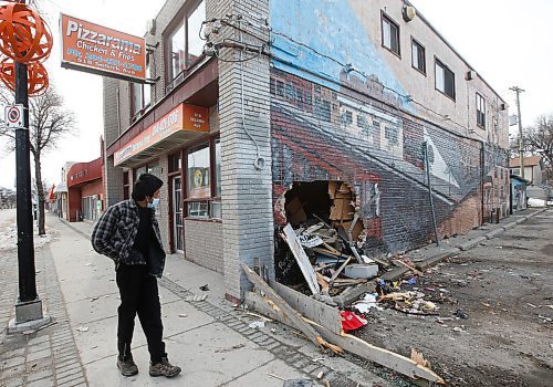 JOHN WOODS / WINNIPEG FREE PRESS
A passer-by checks out the damage to Pizzarama on Selkirk after a car crashed into the building Sunday, April 10, 2022. The driver, who was fleeing police, was killed in the crash.
