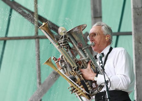 Brandon Sun 14082010 Water sprays out of the musical contraption played by children's entertainer Al Simmons as he entertains the crowd at the 2010 Harvest Sun Music Festival in Kelwood, Man. on a soggy Saturday afternoon. (Tim Smith/Brandon Sun)