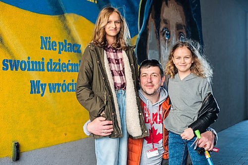 MIKAELA MACKENZIE / WINNIPEG FREE PRESS

Alexander Leontiev poses for a portrait with Yavoslava Chorna (13, left) and Solomiya Chorna (10) in front of a mural in support of Ukraine in Wrzesnia on Tuesday, April 12, 2022. For Melissa story.
Winnipeg Free Press 2022.