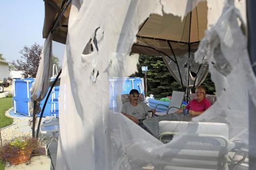MIKE.DEAL@FREEPRESS.MB.CA 100821 - Saturday, August 21, 2010 -  Birdie and David Chuk sit under their destroyed canopy tent in the back yard of their home just south of the Perimeter on McPhillips the morning after a storm moved through with golfball sized hail. MIKE DEAL / WINNIPEG FREE PRESS