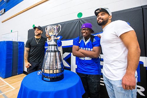 MIKAELA MACKENZIE / WINNIPEG FREE PRESS

Brady Olivera (left), Tyrell Gauthier, George Hambira, and Nic Demski pose for a picture with the Grey Cup at Oak Park School in Winnipeg on Monday, May 2, 2022. For Taylor Allen story.
Winnipeg Free Press 2022.