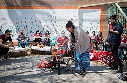 JESSICA LEE / WINNIPEG FREE PRESS

Monique Desjarlais puts sage in the fire while community members sing healing songs at North End Womens Centre on May 5, 2022 for Red Dress Day. 

