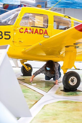 MIKAELA MACKENZIE / WINNIPEG FREE PRESS

Artist Estelle Régnier puts a clear coat onto a floor mural underneath the Musketeer plane at the new Royal Aviation Museum of Western Canada in Winnipeg on Wednesday, May 11, 2022. For Al Small story.
Winnipeg Free Press 2022.