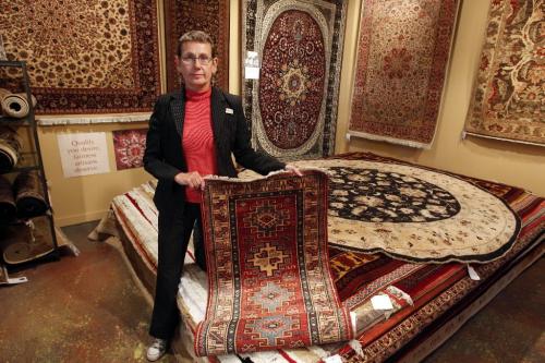 BORIS.MINKEVICH@FREEPRESS.MB.CA  100825 BORIS MINKEVICH / WINNIPEG FREE PRESS Ten Thousand Villages manager Gwen Repeta poses for a photo with some rugs they sell that were made in Pakistan.