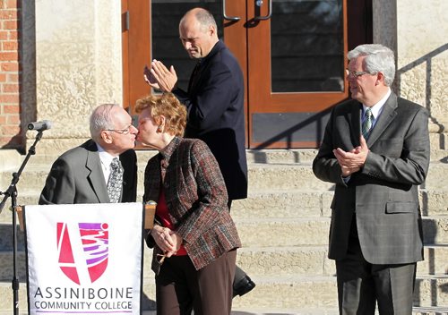 Brandon Sun 01102010 Retired MLA Len Evans and his wife Alice Evans share a kiss as Brandon-East MLA Drew Caldwell looks on during the official unveiling of the Len Evans Centre for Trades and Technology at ACC's north hill campus on Friday morning. (Tim Smith/Brandon Sun)