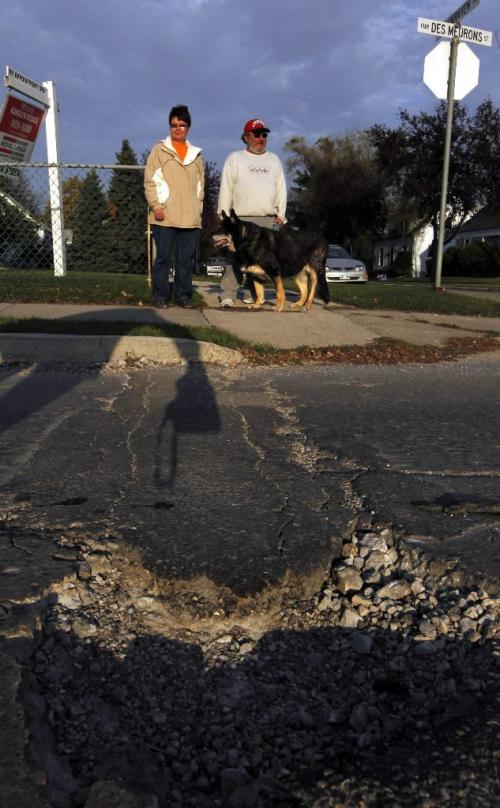 BORIS.MINKEVICH@FREEPRESS.MB.CA  101005 BORIS MINKEVICH / WINNIPEG FREE PRESS Mary and Marcel Berard (and dog Jazz) are in Mary Agnus's story about bad roads. This masive pothole was on Des Meurons St. at Dunraven Ave.