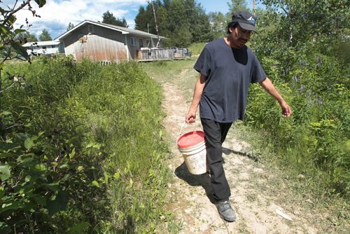 JOE.BRYKSA@FREEPRESS.MB.CA NO RUNNING WATER FEATURE-(See Helen's story)  - Geordie Rae from St.Theresa Point First Nation  carrys water in a five-gallon bucket to his family in the hot sun. For years, he and his wife, children and father-in-law have livedwith no running water. He walks to a home about a kilometre away to get treated water. July 2010, - JOE BRYKSA/WINNIPEG FREE PRESS