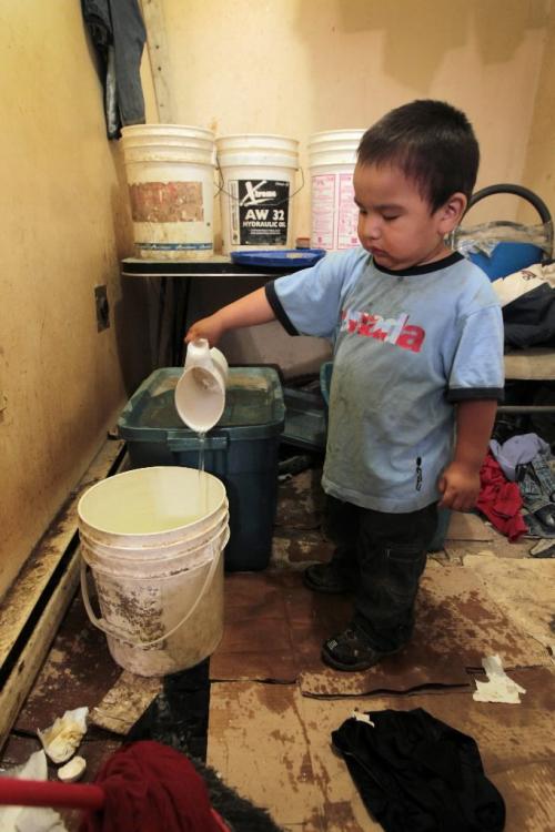 JOE.BRYKSA@FREEPRESS.MB.CA NO RUNNING WATER FEATURE-(See Helen's story)  - Lucas Rae  plays with the treated  water in his home  St.Theresa Point First Nation. The family gets by with just a few buckets of fresh water a day. July 2010, - JOE BRYKSA/WINNIPEG FREE PRESS