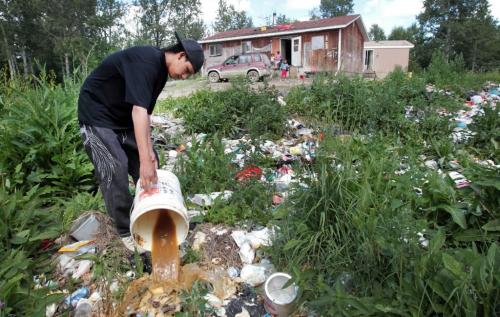 JOE.BRYKSA@FREEPRESS.MB.CA NO RUNNING WATER FEATURE-(See Helen's story)  - Solomon McPherson dumps slop pail full of sewage dumped  in makeshift dump just outside their home in rear at  Garden hill First Nation. The family lives in this home with no running water- July 2010, - JOE BRYKSA/WINNIPEG FREE PRESS