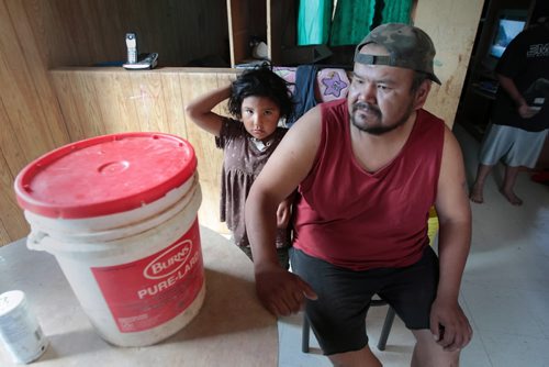 JOE.BRYKSA@FREEPRESS.MB.CA NO RUNNING WATER FEATURE-(See Helen's story)  -   Robert Little  with his daughter Dayna on the Garden Hill First Nation. His family has contamination problem with cistern that has forced family to boil water after family was getting sick. He sits in kitchen and shows small bucket of treated water that the family shares July 2010, - JOE BRYKSA/WINNIPEG FREE PRESS