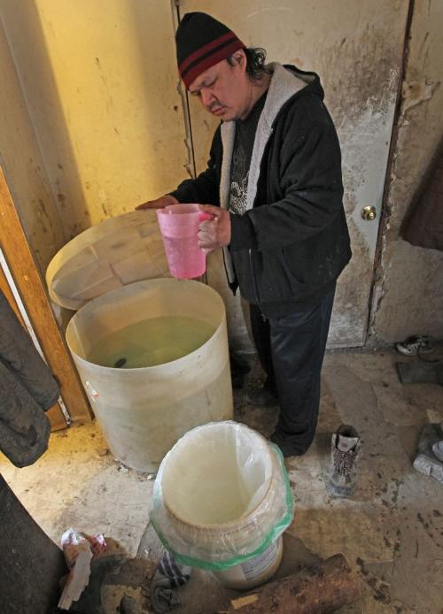 JOE.BRYKSA@FREEPRESS.MB.CA NO RUNNING WATER FEATURE-(See Helen's story)   Paul Harper  scoops water from his parents' storage system at  Wasagamack First Nation - The busy home has no running water and shares treated water sparingly- March 2010, - JOE BRYKSA/WINNIPEG FREE PRESS
